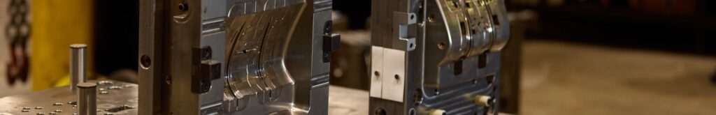 Open halves of a polished injection mold on a toolroom bench