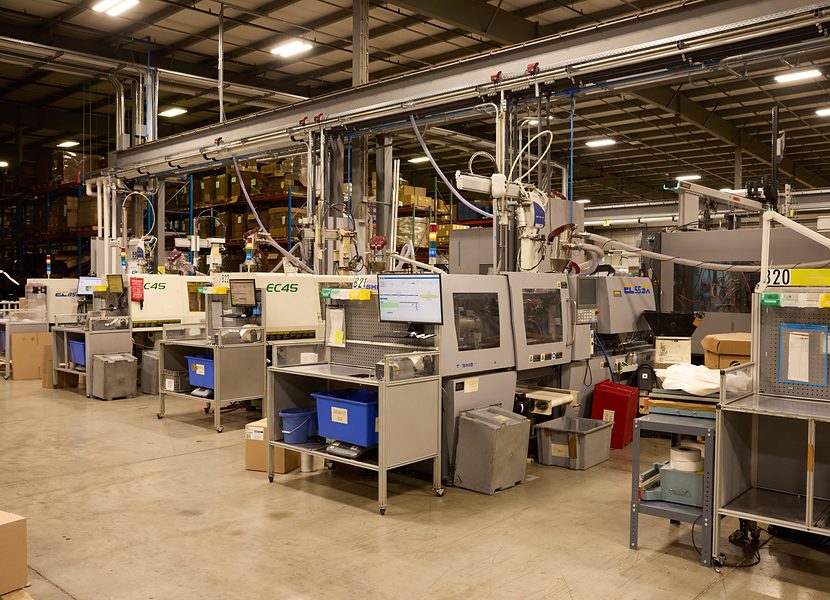 Row of small all-electric injection molding presses with operator workstations