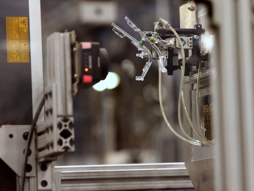 Vision inspection camera checking a clear molded part held by a robot gripper